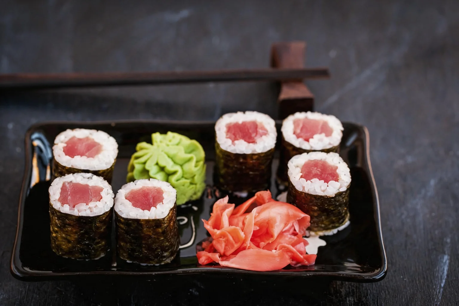 Maki on a black tray, wasabi and ginger.